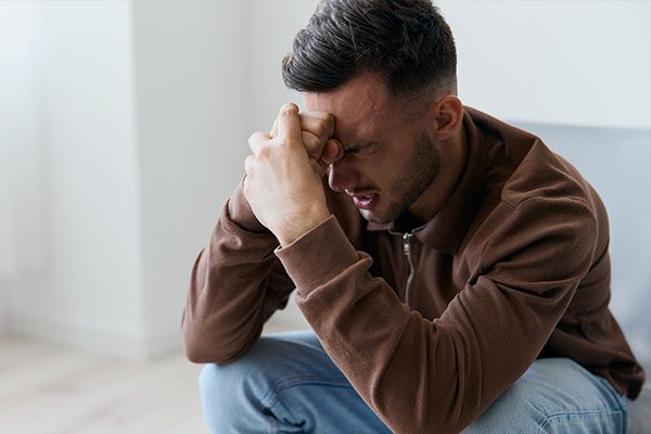 Person sitting with head down.