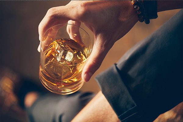Hand holding a glass of whiskey
